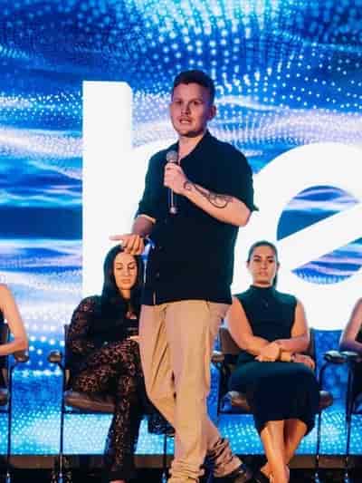 Andreas, co-founder of Ascend Sales, speaking on stage with a microphone